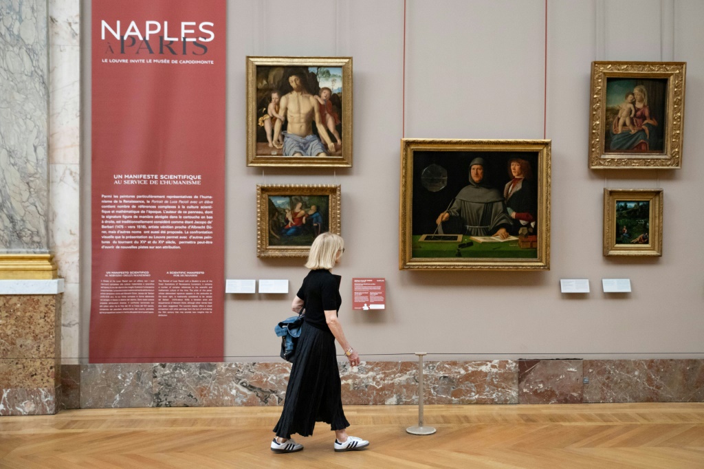 زائرة تمر بجانب لوحات معروضة ضمن معرض "نابولي في باريس" في متحف اللوفر في باريس في السادس من حزيران/يونيو 2023 (ا ف ب)