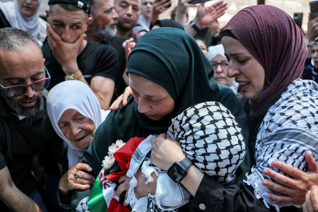     مروة التميمي تحتضن ابنها محمد البالغ من العمر 3 سنوات والذي قتل الأسبوع الماضي برصاص القوات الإسرائيلية خلال جنازته في الضفة الغربية المحتلة في 6 حزيران/يونيو 2023 (ا ف ب)
