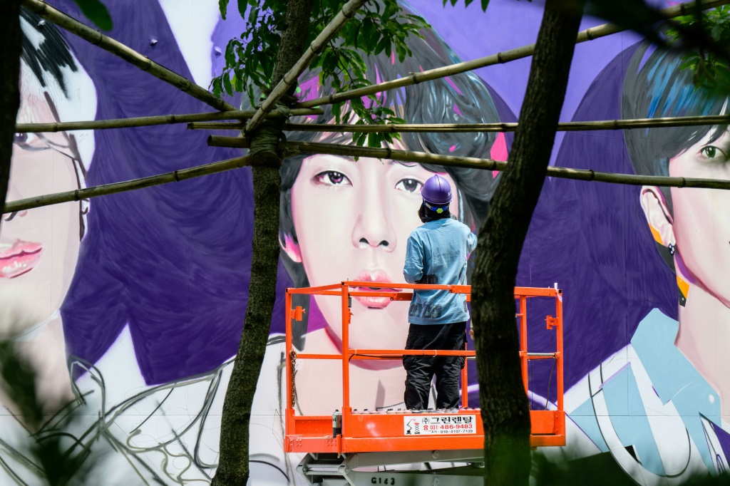 فنان يستخدم عبوة رذاذ لإنجاز جدارية بصور أعضاء فرقة "بي تي اسط في سيول في 12 حزيران/يونيو 2023 (ا ف ب)