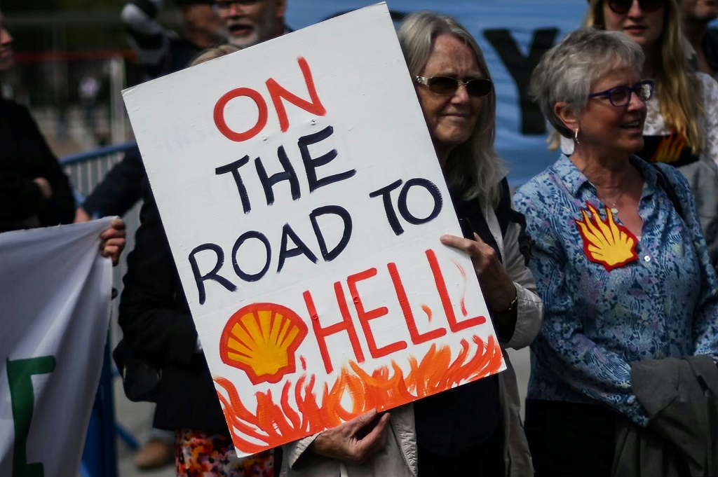 ناشط مناخي يحمل لافتة خارج الاجتماع العام السنوي لشركة شل الشهر الماضي في لندن (أ ف ب)   