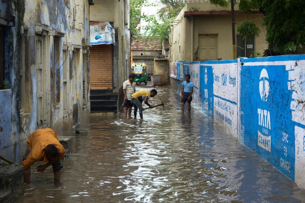 رجال يعملون على تجفيف ممر مليء بالمياه بعد هطول أمطار غزيرة في مدينة ماندفي على بعد 100 كيلومتر جنوب شرق ميناء جاكو في 15 حزيران/يونيو 2023 قبل مرور إعصار بيبارجوي (ا ف ب)