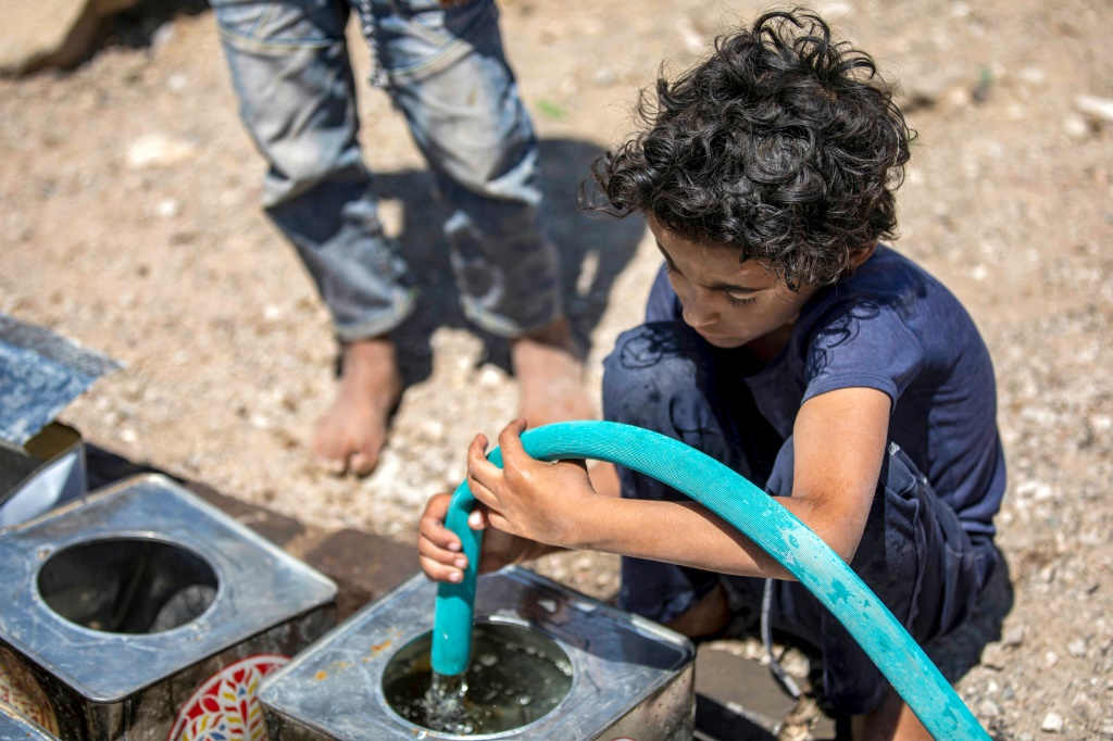 فتى يملأ حاوياته بالمياه من صهريج على مشارف مدينة تعز في جنوب غرب اليمن في 8 حزيران/يونيو 2023 (ا ف ب)