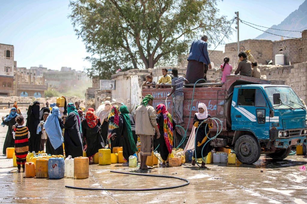 أشخاص يتجمّعون قرب صهريج مياه لملء حاوياتهم على مشارف مدينة تعز في جنوب غرب اليمن في 8 حزيران/يونيو 2023 (أ ف ب)