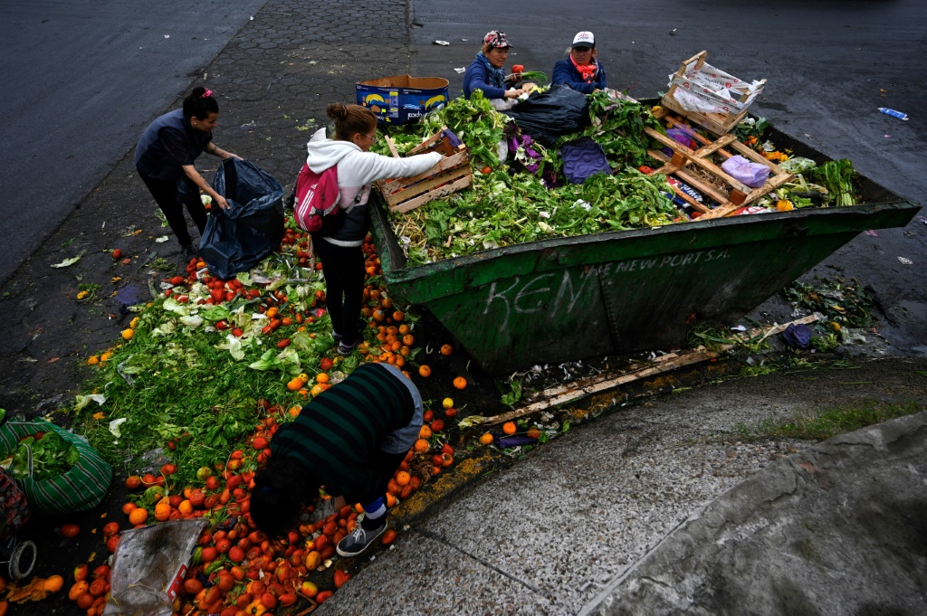 صورة مؤرخة في 9 حزيران/يونيو 2023 لأشخاص يجمعون الفواكه والخضر من حاوية نفايات في سوق في بوينوس آيرس (ا ف ب)