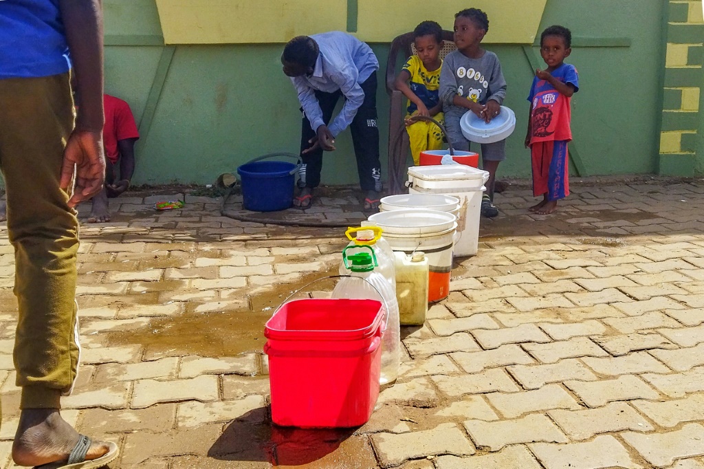           أطفال ورجال سودانيون يملأون حاويات مياه في ود مدني في السودان على بعد 200 كيلومترا جنوب العاصمة الخرطوم في 20 حزيران/يونيو 2023 (أ ف ب)