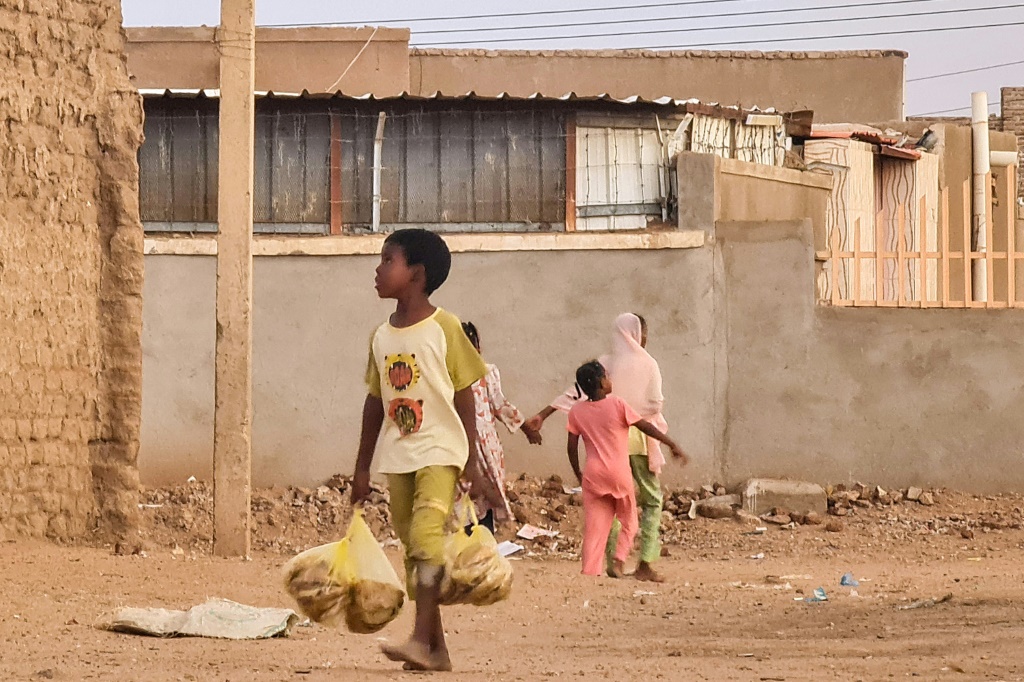     طفل يحمل أكياس الخبز في أحد شوارع الخرطوم في 20 حزيران/يونيو 2023 (أ ف ب)