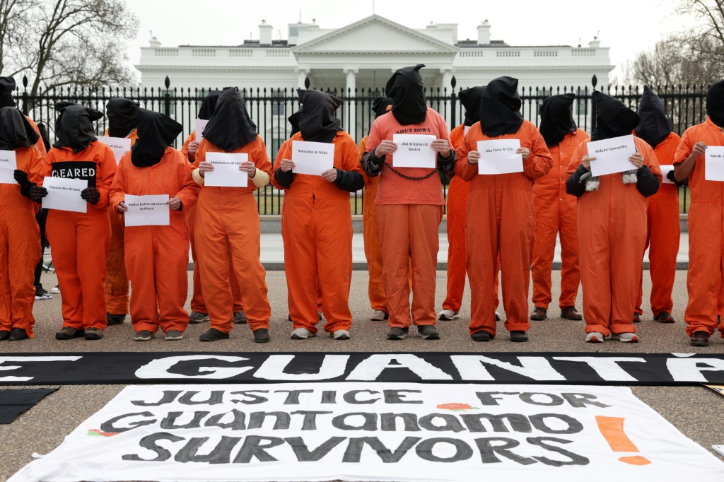     نشطاء يرتدون ملابس السجن البرتقالية احتجاجا في يناير على استمرار احتجاز حوالي 30 شخصا في السجن العسكري الأمريكي في خليج غوانتانامو ، كوبا (أ ف ب)