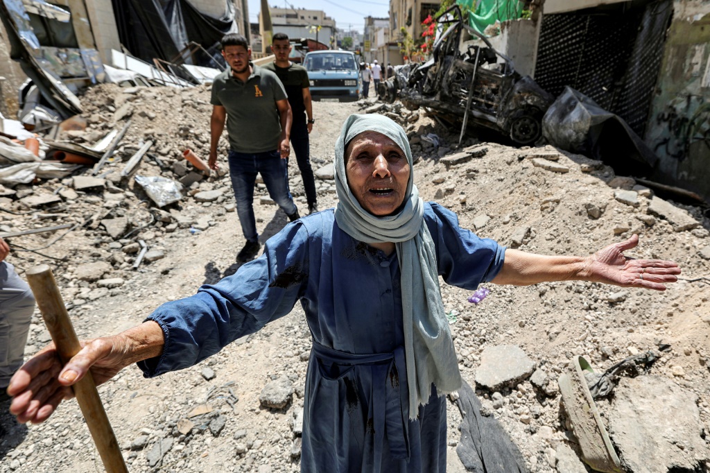     سيدة فلسطينية مسنة تقف على ركام من الحجارة عند أحد أزقة مخيم جنين في الضفة الغربية المحتلة في الخامس من تموز/يوليو 2023 بعد أن اعلن الجيش الإسرائيلي انتهاء عمليته العسكرية الأكبر منذ سنوات في الضفة الغربية المحتلة (أ ف ب)
