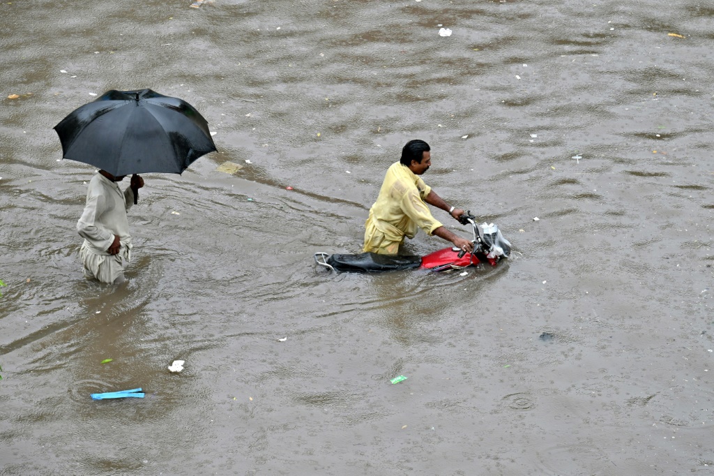     سائق دراجة نارية يعبر شارعًا غمرته المياه بعد هطول أمطار غزيرة في لاهور في 5 تموز/يوليو 2023 (أ ف ب)
