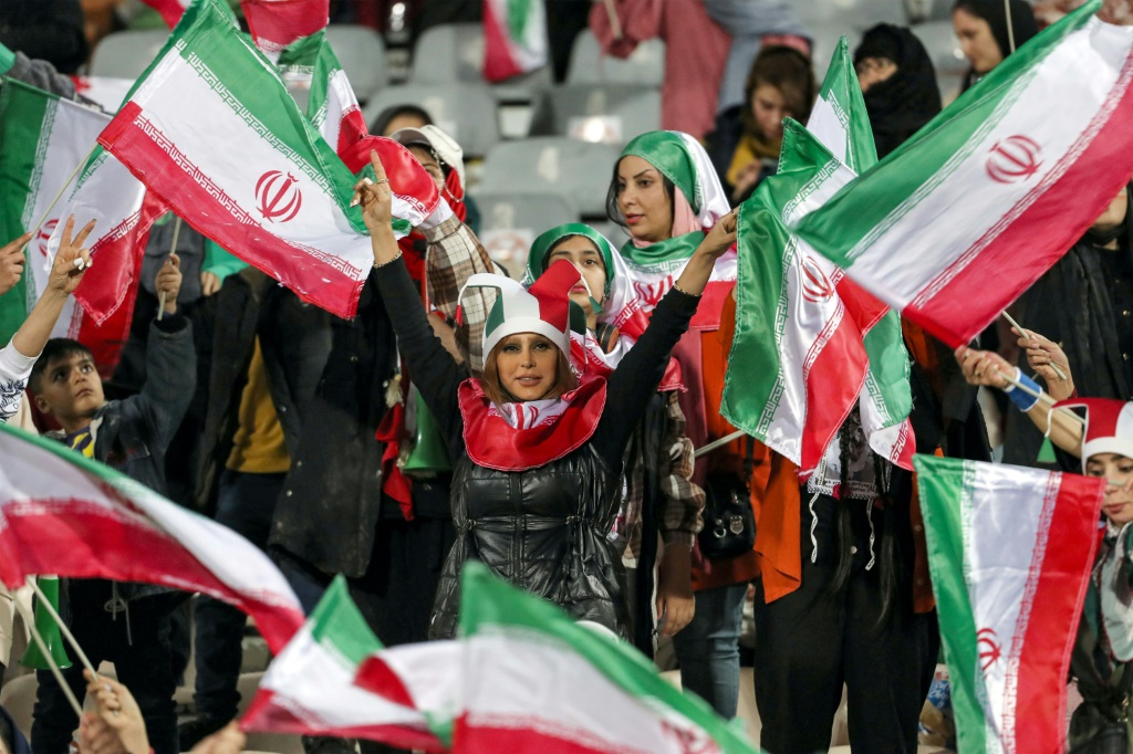 مشجعات إيرانيات يلوّحن بأعلام بلادهنّ خلال مباراة ودية مع روسيا على ملعب آزادي في العاصمة طهران. 23 آذار/مارس 2023 (ا ف ب)