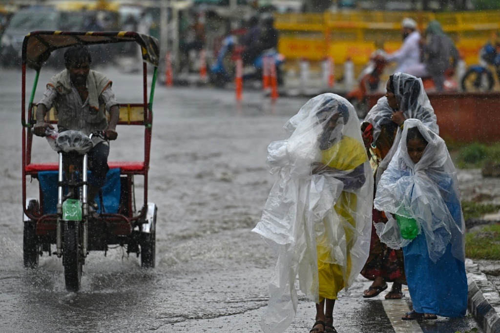 عابرون يستخدمون الأغطية البلاستيكية لحماية أنفسهم من الأمطار في نيودلهي في 10 تموز/يوليو 2023 (ا ف ب)