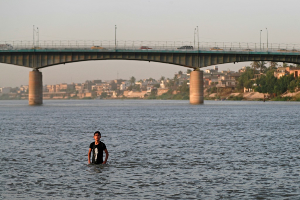شاب يسير في نهر دجلة في العاصمة العراقية بغداد في 12 تموز/يوليو 2023 (ا ف ب)