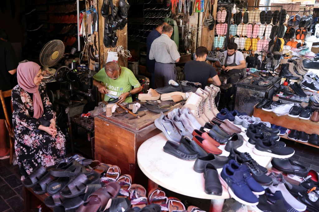 عمال يصلحون أحذية فيما ينتظر زبائن في محل السكاف أحمد البزري في مدينة صيدا الساحلية في جنوب لبنان في 11 تموز/يوليو 2023 (ا ف ب)