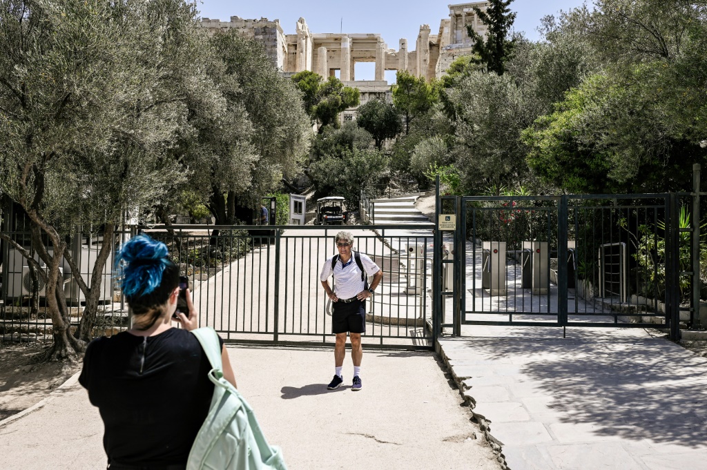     سائح يقف لالتقاط صورة عند مدخل الأكروبوليس المغلق بسبب موجة الحر في أثينا في 14 تموز/يوليو 2023 (أ ف ب)   