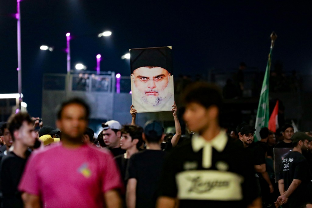 أتباع رجل الدين الشيعي العراقي مقتدى الصدر يحملون صورته عالياً خلال مظاهرة بعد أن اعتقدوا أن القرآن قد تعرض للتدنيس في الدنمارك (أ ف ب)   