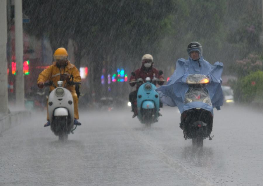 في الصورة الملتقطة يوم 24 يونيو 2023، مواطنون يركبون دراجات كهربائية تحت المطر في مدينة ناننينغ، حاضرة منطقة قوانغشي ذاتية الحكم لقومية تشوانغ جنوبي الصين (شينخوا)