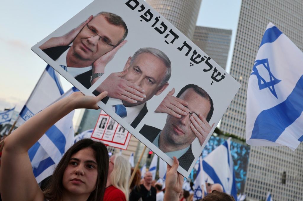 متظاهرة تحمل لافتة خلال مسيرة في تل أبيب في 22 تموز/يوليو 2023 للاحتجاج على مشروع قانون الإصلاح القضائي (ا ف ب)