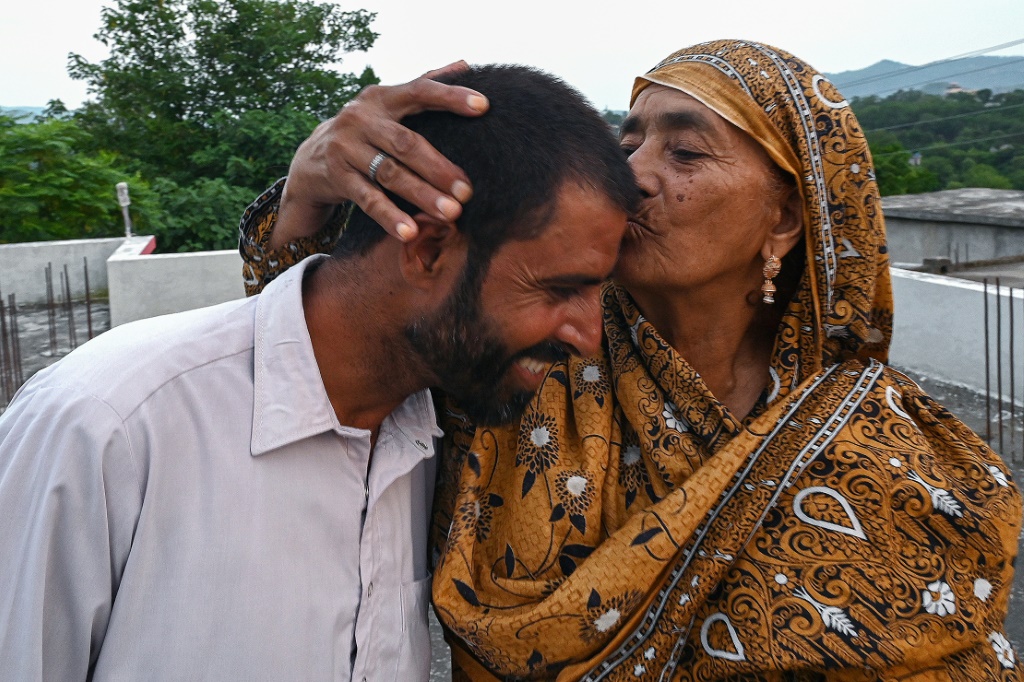     محمد نعيم بات ، الذي تخلى عن محاولة محفوفة بالمخاطر للوصول إلى أوروبا ، قبلته والدته راضية لطيف في منزلهم في باكستان (أ ف ب)   