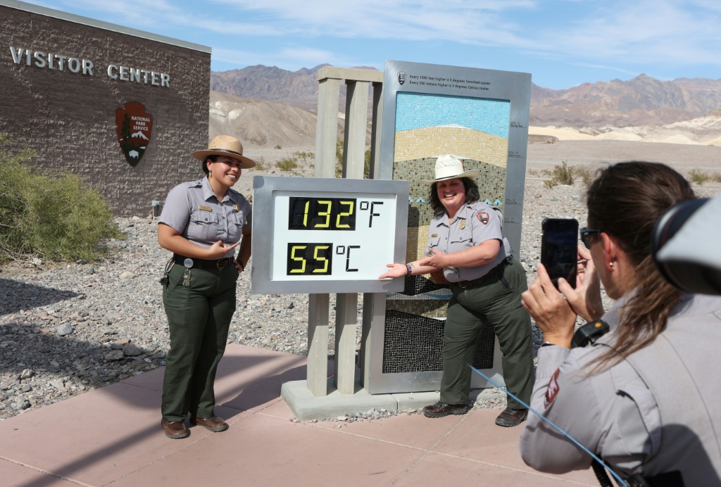 عناصر من الشرطة المحلية قرب مقياس حرارة يشير إلى 55 درجة مئوية في وادي الموت بولاية كاليفورنيا في 16 حزيران/يونيو 2023 (ا ف ب)