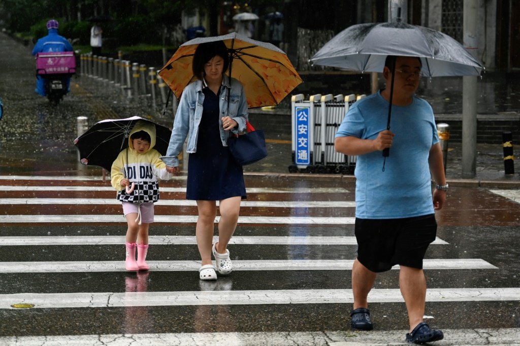 مارة يحملون مظلات وسط تساقط أمطار غزية فوق العاصمة الصينية بكين في 30 تموز/يوليو 2023 (ا ف ب)