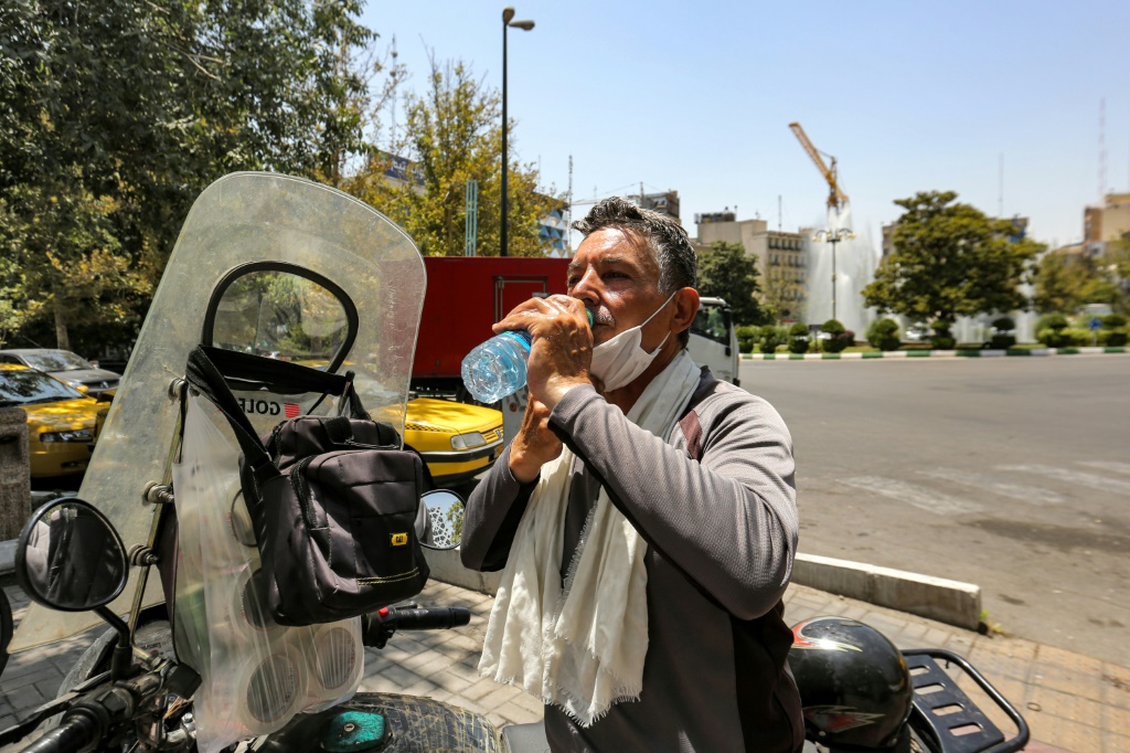 سائق دراجة نارية يأخذ استراحة من حرارة طهران في 11 يوليو 2023 (أ ف ب)   