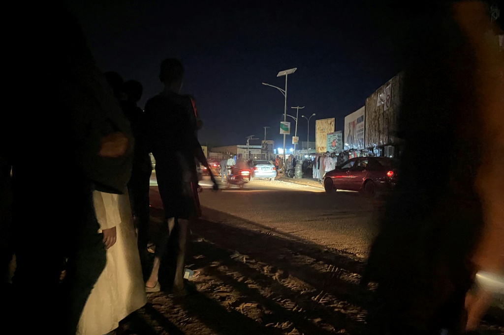 شبان يراقبون حركة السير ليلا عند دوار الفرنكوفونية في نيامي في الرابع من آب/أغسطس 2023 (ا ف ب)