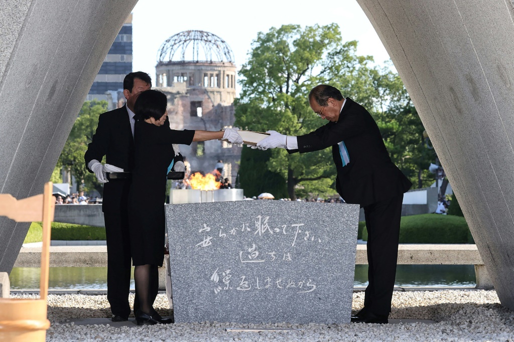 رئيس بلدية هيروشيما كازومي ماتسوي (يمين) وممثلان عن عائلات ضحايا قصف المدينة اليابانية بالقنبلة الذرية أمام النصب التذكاري للضحايا في 6 آب/أغسطس 2023 في الذكرى الـ78 لأول هجوم بقنبلة ذرية في العالم (ا ف ب)