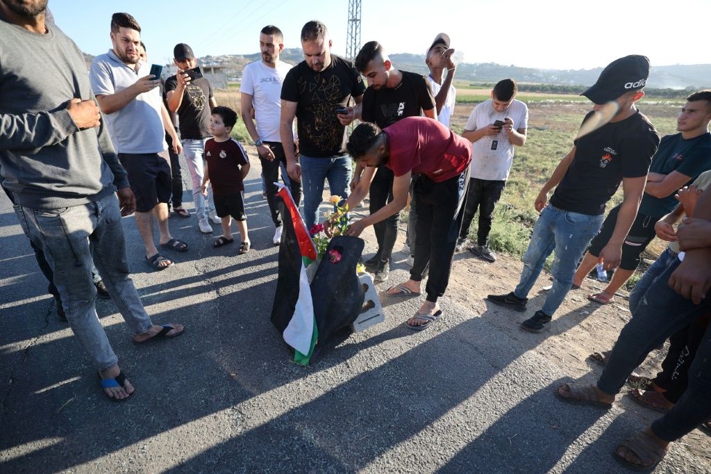 فلسطينيون يضعون الورود في موقع قتلت فيه القوات الإسرائيلية ثلاثة شبان فلسطينيين قرب مخيم جنين في الضفة الغربية في السادس من آب/أغسطس 2023 (ا ف ب)