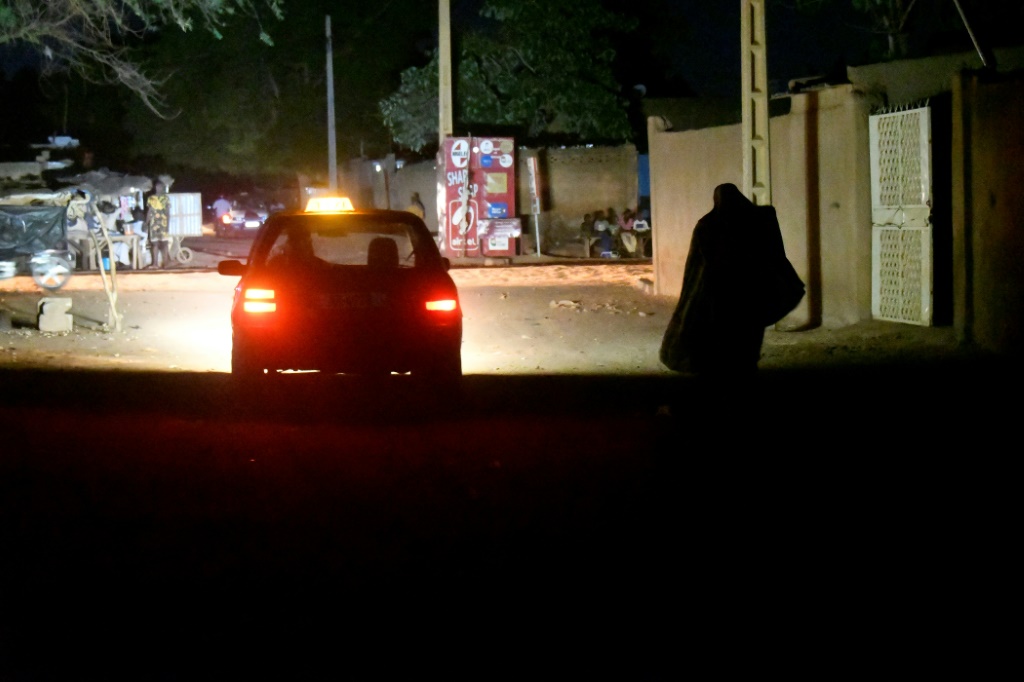     امرأة تمشي على أحد الطرق أثناء انقطاع التيار الكهربائي في أجزاء من نيامي عاصمة النيجر (أ ف ب)   