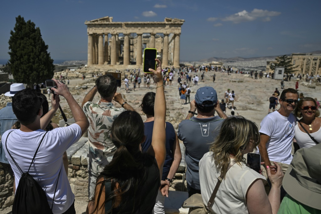 سائحون يلتقطون صوراً أمام معبد البارثينون خلال زيارتهم موقع أكروبوليس الأثري في أثينا بتاريخ 14 حزيران/يونيو 2023 (ا ف ب)