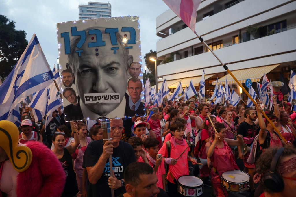 متظاهرون يرفعون صورا وشعارات مناهضة لخطة التعديلات القضائية لرئيس الحكومة الإسرائيلية بنيامين نتانياهو خلال تحرك في تل أبيب في 12 آب/أغسطس 2023 (ا ف ب)