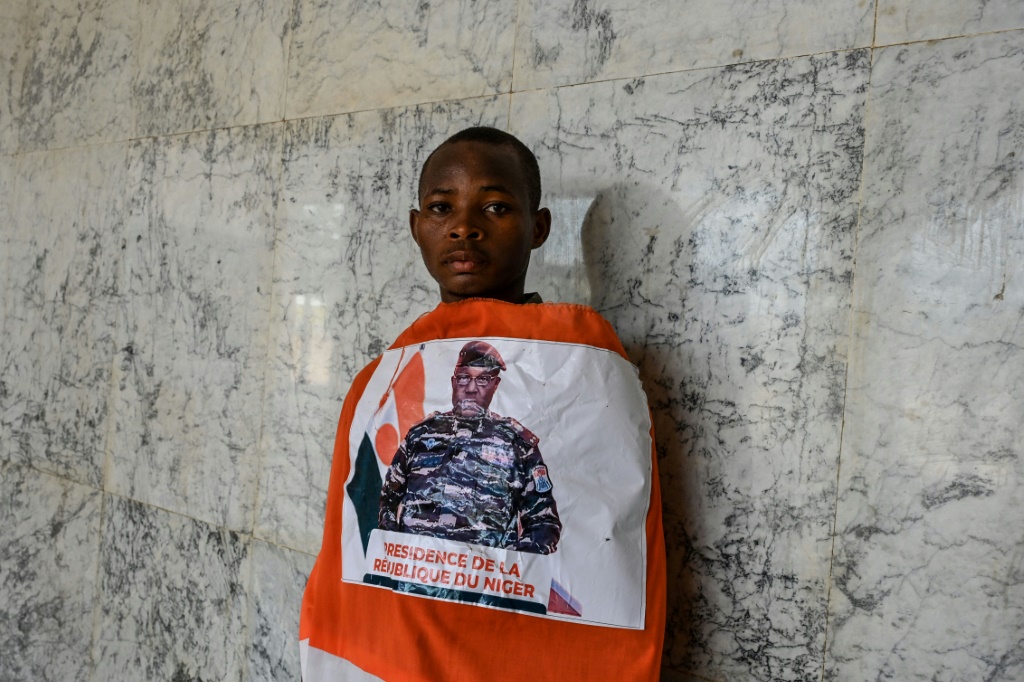 شاب يلف نفسه بعلم للنيجر تتوسطه صورة قائد الانقلاب الجنرال عبد الرحمن تياني في إستاد في نيامي في 13 آب/أغسطس 2023 (ا ف ب)
