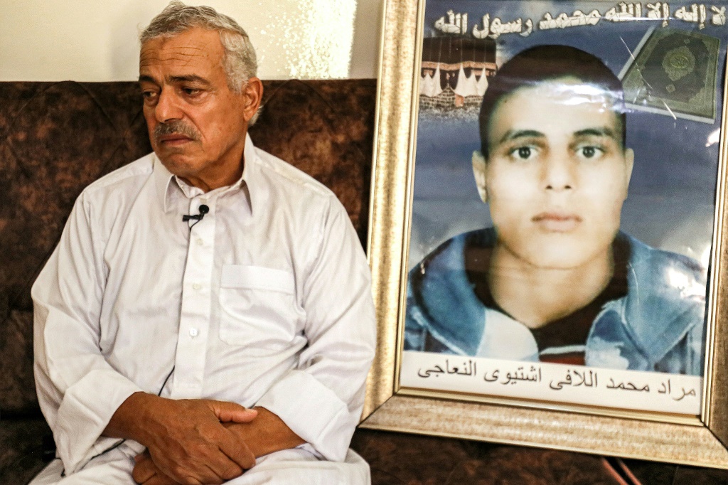 محمد اللافي يجلس أمام صورة نجله مراد خلال مقابلة في منزله في ترهونة بتاريخ 5 آب/أغسطس 2023 (ا ف ب)