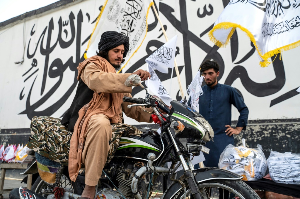  شخص يبيع أعلاما لإمارة أفغانستان الإسلامية، وهو الاسم الذي أطلقته سلطات طالبان على أفغانستان، في كابول في 14 آب أغسطس 2023 (أ ف ب)   