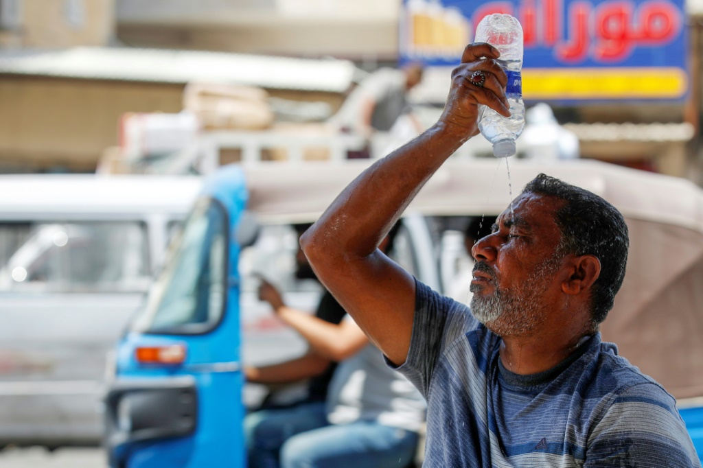 رجل يضع الماء على وجهه في بغداد ليقاوم درجات الحرارة المرتفعة في 13 آب/أغسطس 2023 (أ ف ب)   