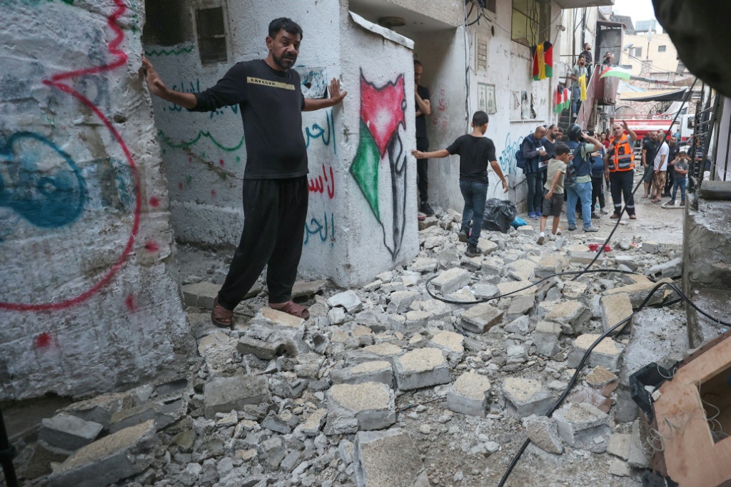 طواقم الطوارئ الفلسطينية والسكان يتفقدون الأضرار في أعقاب الغارة الإسرائيلية على مخيم بلاطة للاجئين في الضفة الغربية المحتلة (أ ف ب)