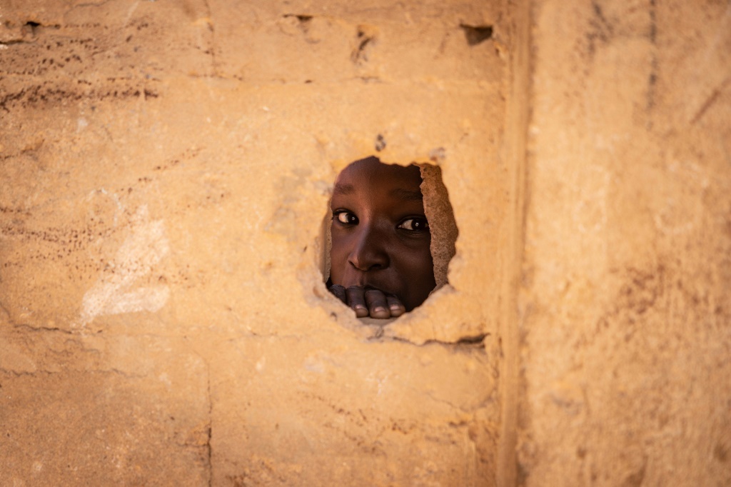 صبي ينظر من خلال ثقب في جدار في مدرسة في ساكورا ، في منطقة تيلابيري التي ضربها الجهاديون في النيجر. (أ ف ب)   