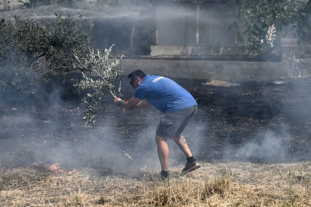 صورة مؤرخة في 23 آب/أغسطس 2023 لأحد سكان ديكيلا اليونانية يحاول إخماد نيران مع اقتراب الحرائق من بلدته (ا ف ب)