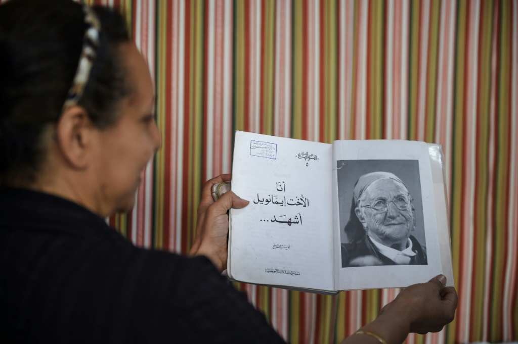 امرأة تحمل كتاباً عليه صورة الأخت إيمانويل في مدرسة المحبة في عزبة النخل في شمال العاصمة المصرية القاهرة في 13 تشرين الأول/أكتوبر 2018 (ا ف ب)
