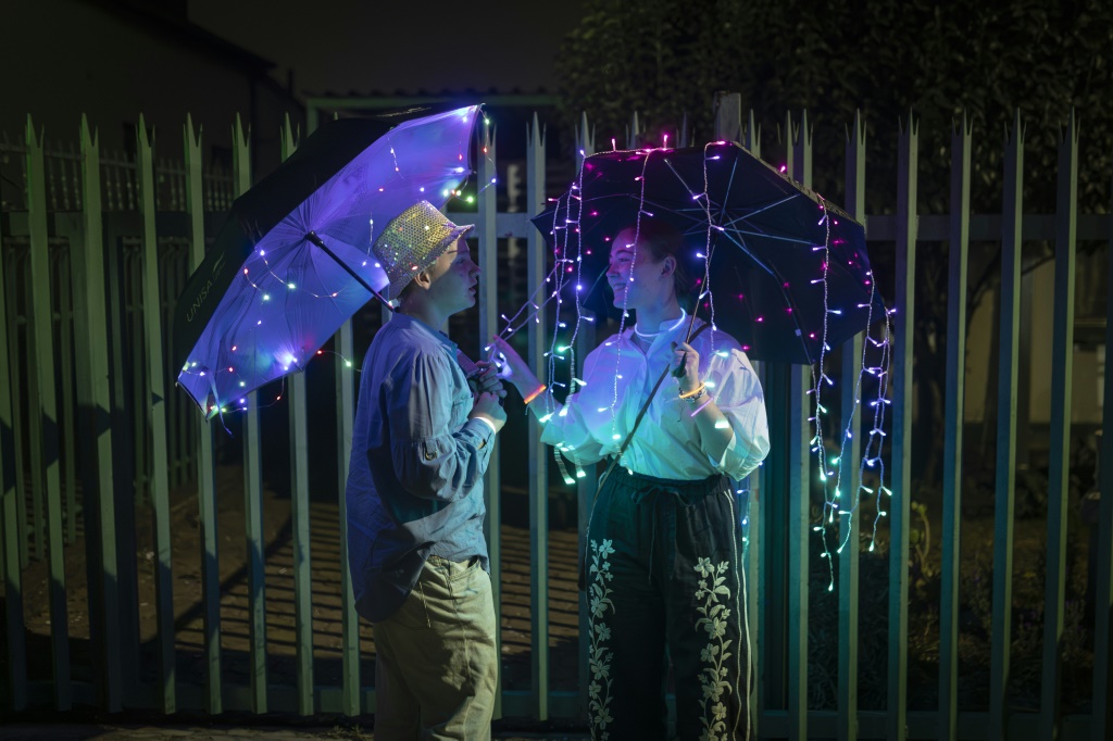 اثنان من سكان حي بريكستون في جوهانسبرغ يحملان مظلّتين مزيّنتين بأشرطة من الأضواء يشاركان في مهرجان الأنوار في عاصمة جنوب إفريقيا الاقتصادية في 2 أيلول/سبتمبر 2023 (ا ف ب)