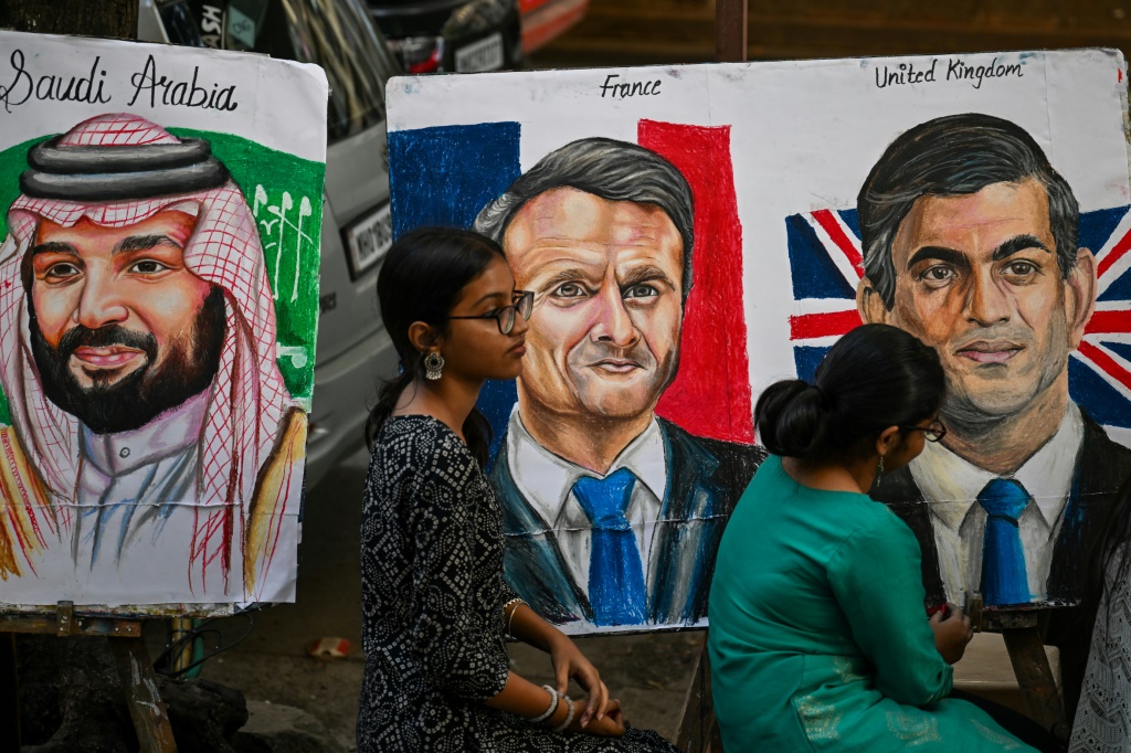 يضع الطلاب اللمسات النهائية على لوحات ولي العهد السعودي الأمير محمد بن سلمان والرئيس الفرنسي إيمانويل ماكرون ورئيس الوزراء البريطاني ريشي سوناك (من اليسار)، قبل قمة مجموعة العشرين (أ ف ب)   