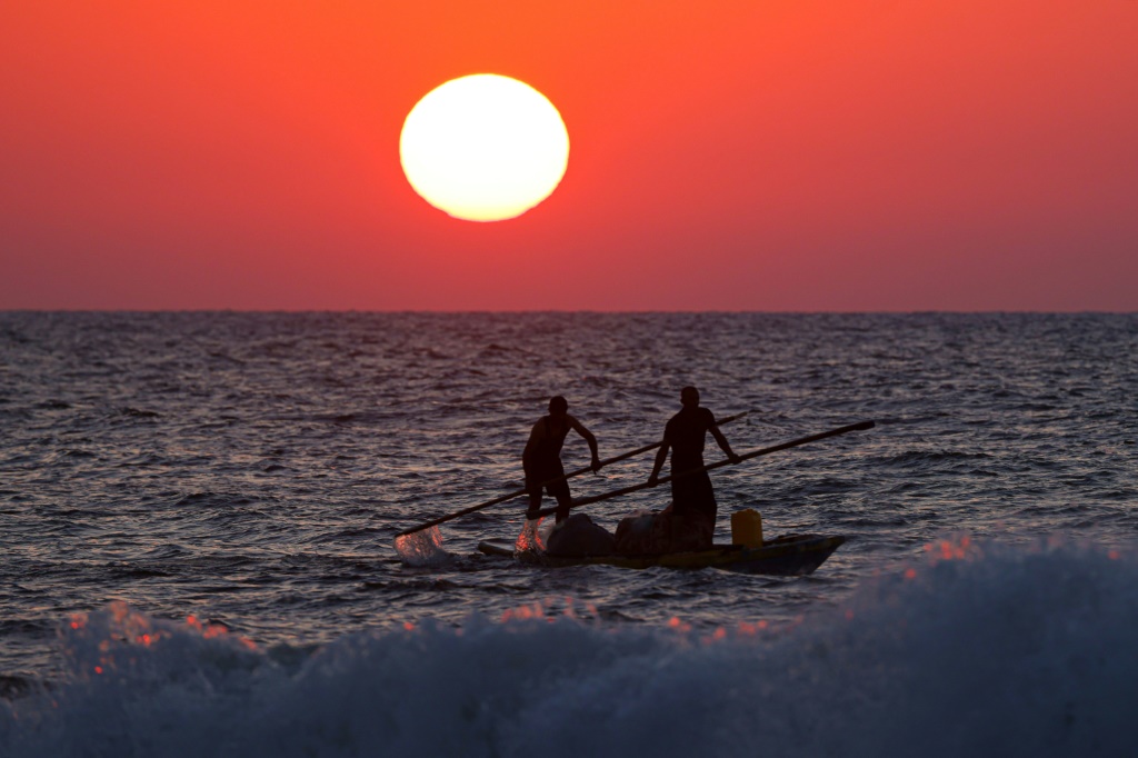 صيادون فلسطينيون عائدون إلى الساحل في قوارب الكاياك أثناء غروب الشمس في مدينة غزة، في 5 أيلول/سبتمبر 2023 (أ ف ب)   
