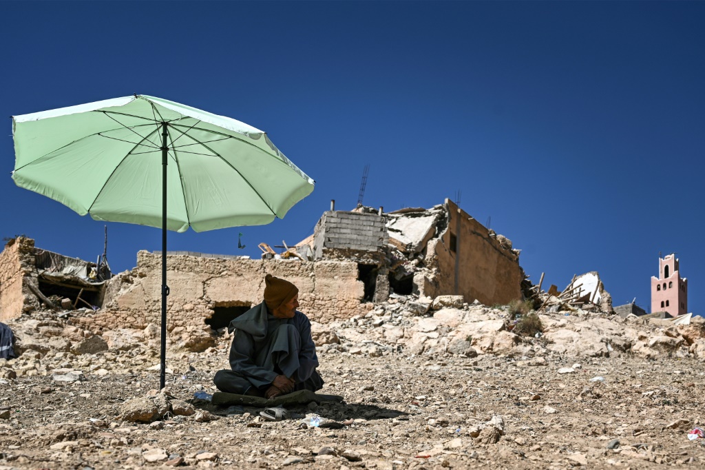 أحد الأهالي يجلس تحت مظلة وسط دمار مبان في مولاي إبراهيم، عقب زلزال 8 أيلول/سبتمبر 2023 (أ ف ب)   