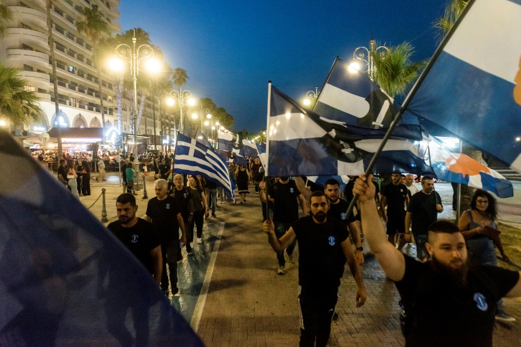 مناصرون لحزب إيلام القبرصي يحملون أعلام اليونان والحزب في مسيرة معارضة للمهاجرين غير الشرعيين في الجزيرة في مدينة لارنكا الساحلية في 16 حزيرانيونيو 2023 (ا ف ب)