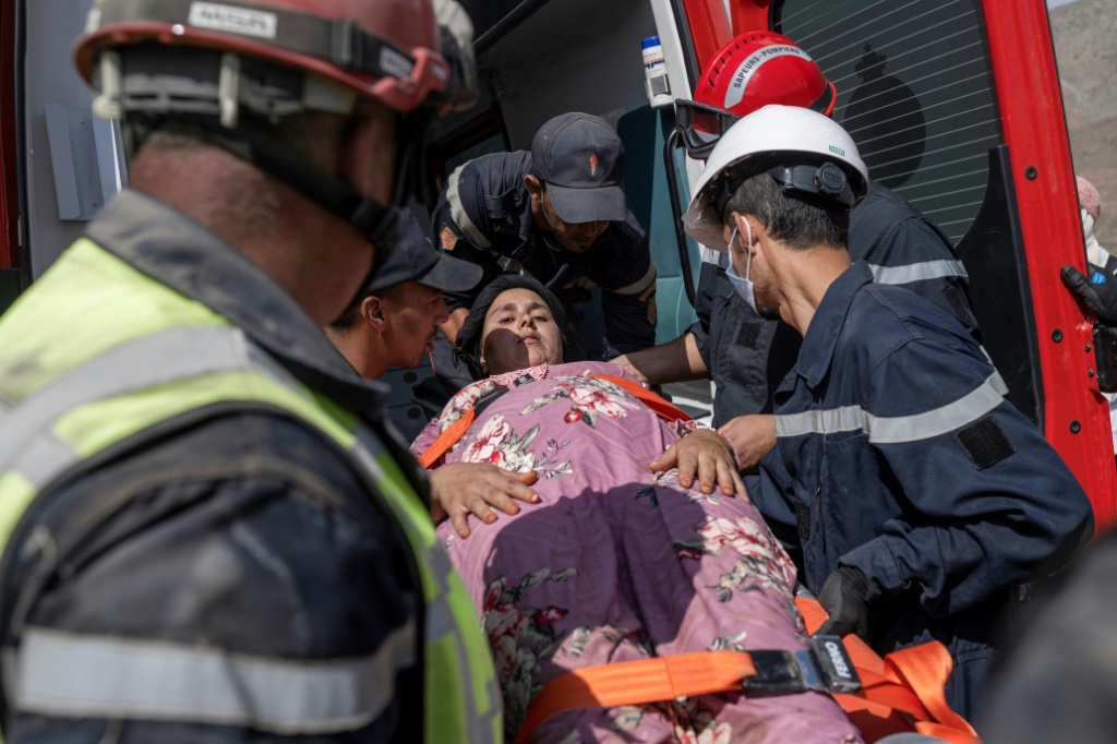 عمال الإنقاذ يقومون بإجلاء إحدى الناجيات من زلزال المغرب بعد أن أنقذوها من تحت الأنقاض (أ ف ب)   