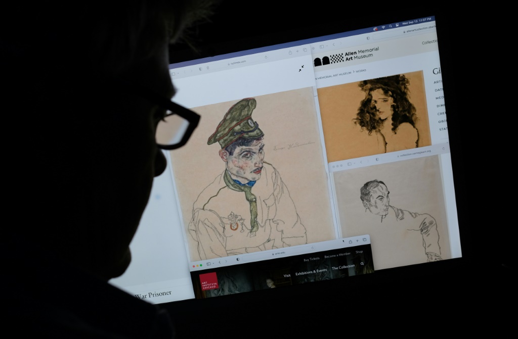 رجل ينظر على شاشة الكمبيوتر في 13 أيلول/سبتمبر 2023 في لوس أنجليس إلى ثلاثة أعمال للفنان النمسوي إيغون شيله صادرها القضاء الأميركي (ا ف ب)