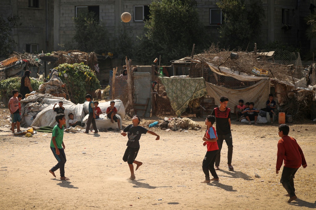 فتية فلسطينيون يلعبون كرة القدم في أحد الأحياء الفقيرة في غزة وسط ارتفاع درجات الحرارة وانقطاع التيار الكهربائي في 31 تموز/يوليو 2023 (أ ف ب)   