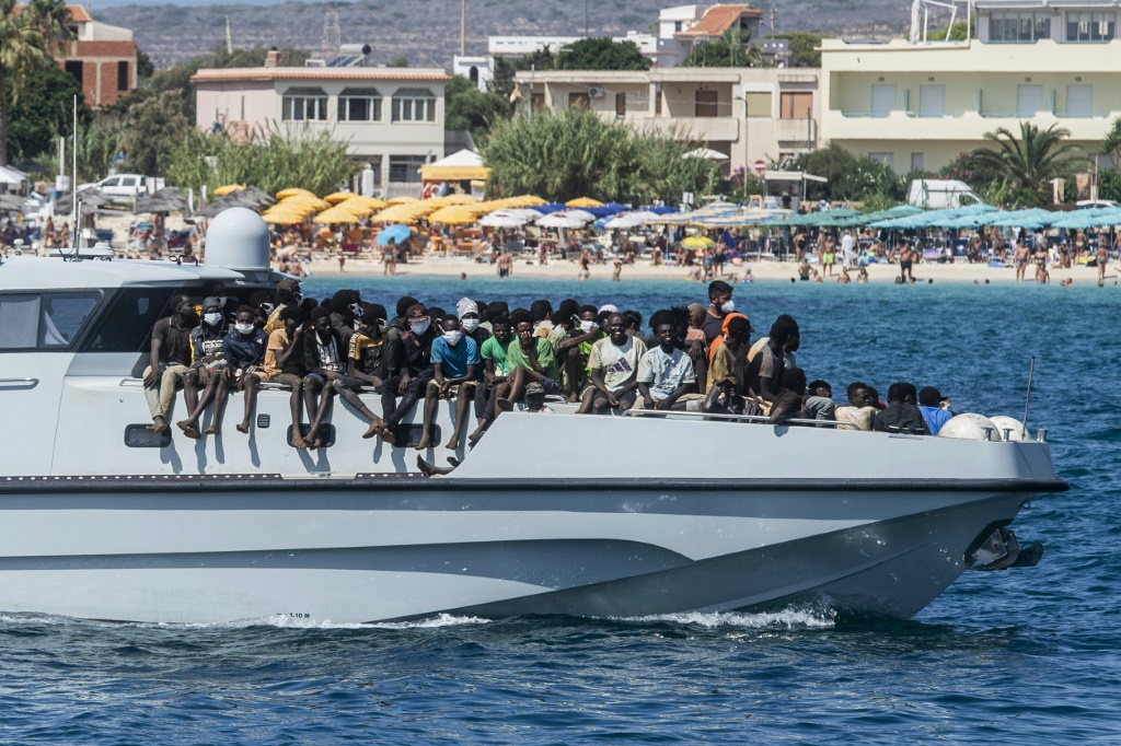 مهاجرون على متن قارب تابع للشرطة الإيطالية لدى وصوله الى ميناء جزيرة لامبيدوسا في 15 أيلول/سبتمبر 2023 (أ ف ب)   