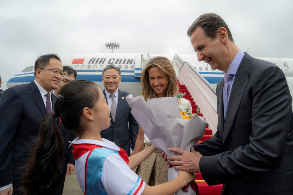 الرئيس السوري بشار الأسد والسيدة الأولى أسماء الأسد أثناء استقبالهما عند وصولهما إلى مطار بكين، في 21 أيلول/سبتمبر (أ ف ب)   