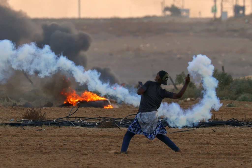 متظاهر فلسطيني يعاود رمي قنبلة مسيلة للدموع اطلقتها القوات الاسرائيلية على الحدود مع قطاع غزة (ا ف ب)